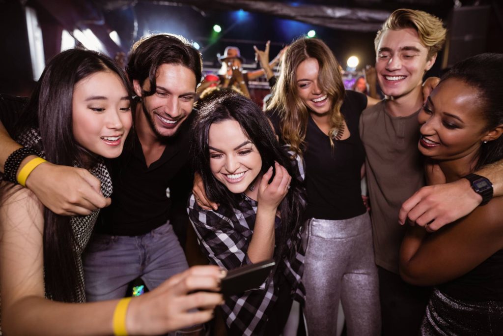 cheerful friends looking at a mobile phone